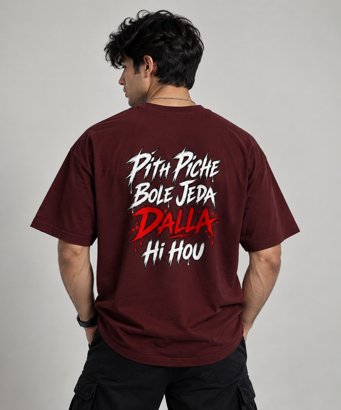 A man wearing a maroon t-shirt from the back, featuring a bold graphic print in white and red text that reads 'Pith Piche Bole Jeda Bole Joda Hi Hou'.