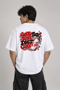 A man viewed from behind wearing a white t-shirt with a large red and black retro-style graphic on the back that reads 'Good Food Better Diet Coke' alongside a Diet Coke can illustration, paired with black cargo pants against a neutral studio background.