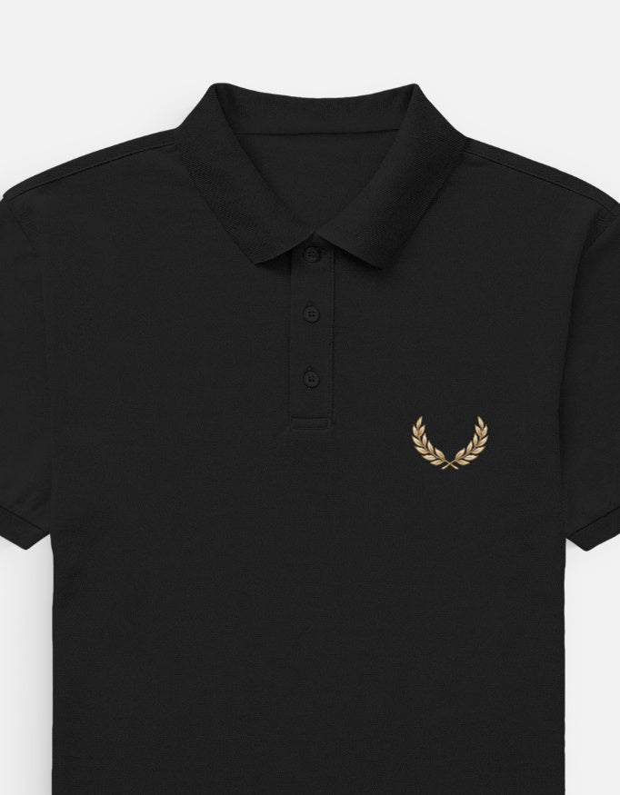 A black short-sleeve polo shirt with a small yellow and white embroidered graphic on the left chest, shown against a light gray background.