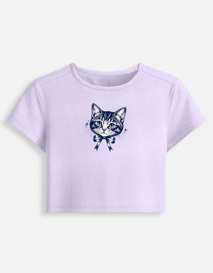 A lavendar l short-sleeve crop top featuring a detailed navy blue graphic of a tabby cat wearing a bow on the front, displayed against a light gray background.