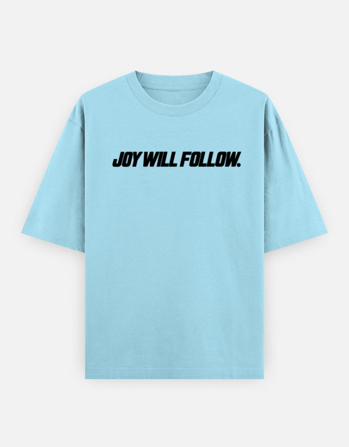 A light blue short-sleeve t-shirt with the phrase 'JOY WILL FOLLOW.' printed in black across the chest, displayed on a clean, light gray background.