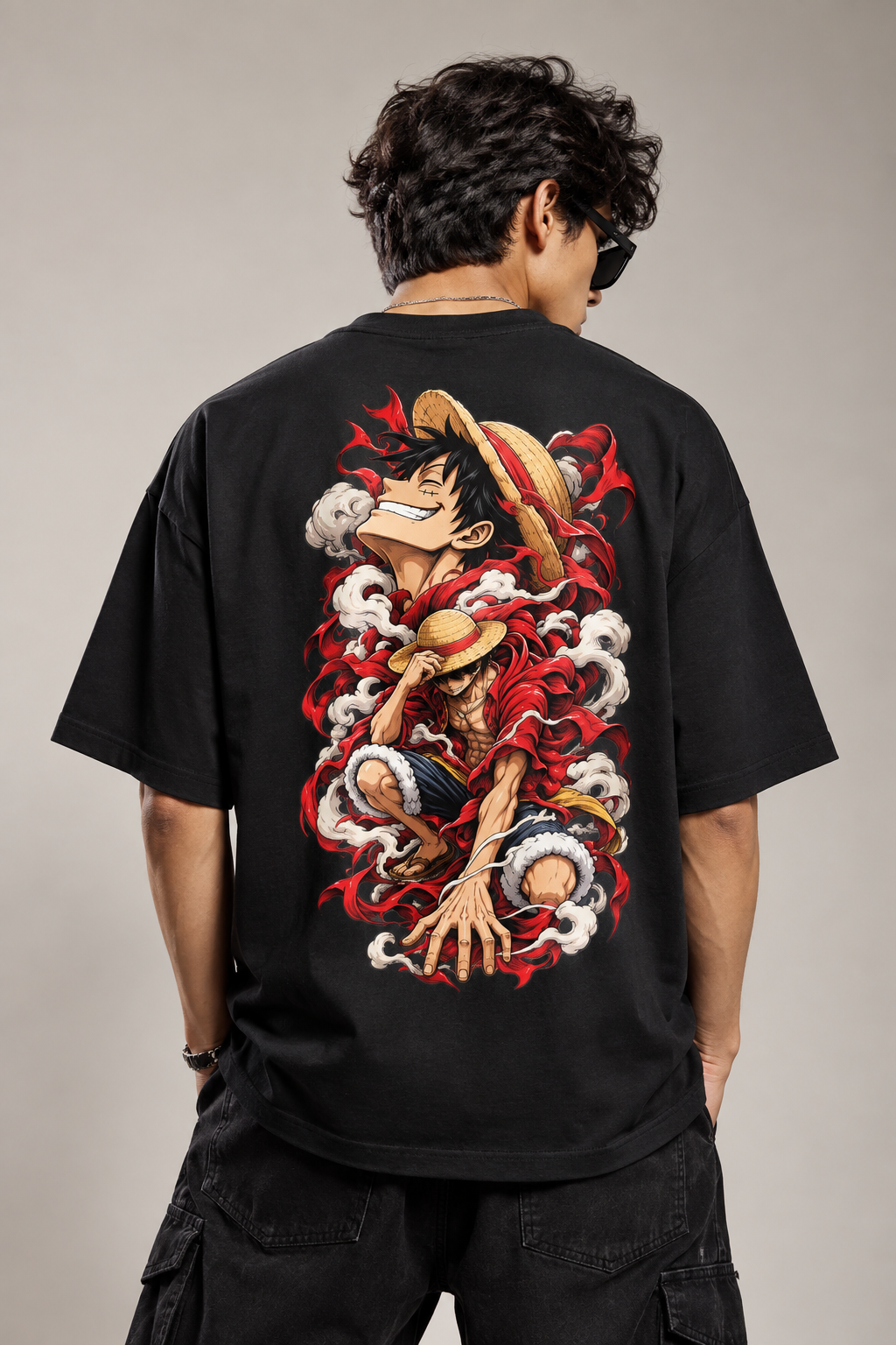 A man wearing a black graphic t-shirt, viewed from behind. The shirt features a large, detailed back print of the anime character Luffy from One Piece, depicted with his straw hat and surrounded by red and white waves.