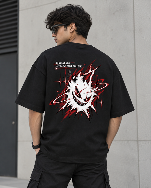 A man wearing a black oversized t-shirt from the back, featuring a large graphic print of a white skull with a red ring and red lightning effects, with the text 'DO WHAT YOU LOVE, JET WILL FOLLOW.' on a gray concrete wall.