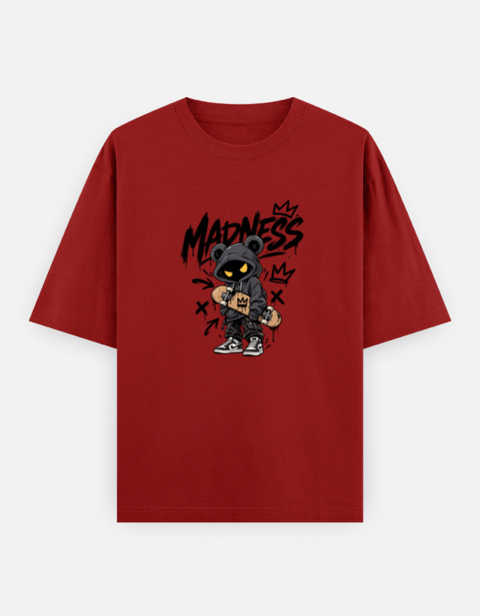 A red short-sleeve t-shirt with a central graphic of a cartoon bear wearing a black cap and sunglasses, with the word 'MADNESS' in black graffiti-style lettering above it, displayed on a light gray background.
