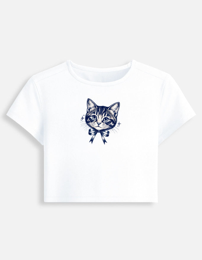 A white short-sleeve crop top t-shirt featuring a detailed navy blue line art illustration of a tabby cat wearing a bow on the chest, displayed against a light gray background.
