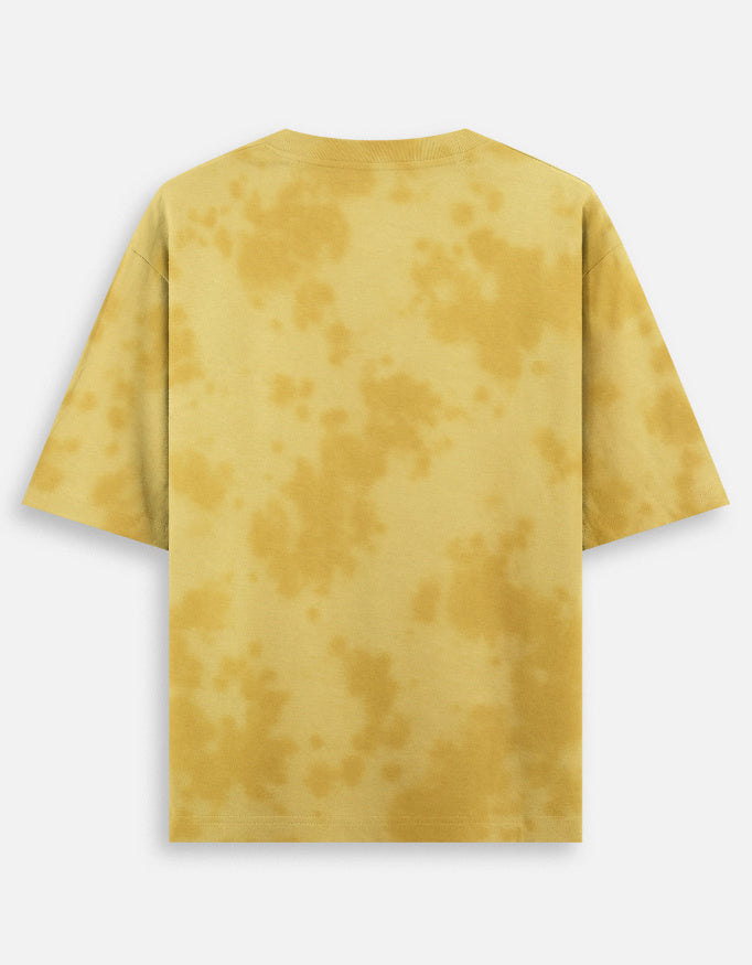 Model wearing an oversized tie-dye t-shirt with relaxed streetwear styling in a studio yellow back